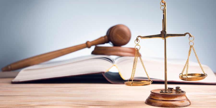 Photo of scale with a gavel and book in the background