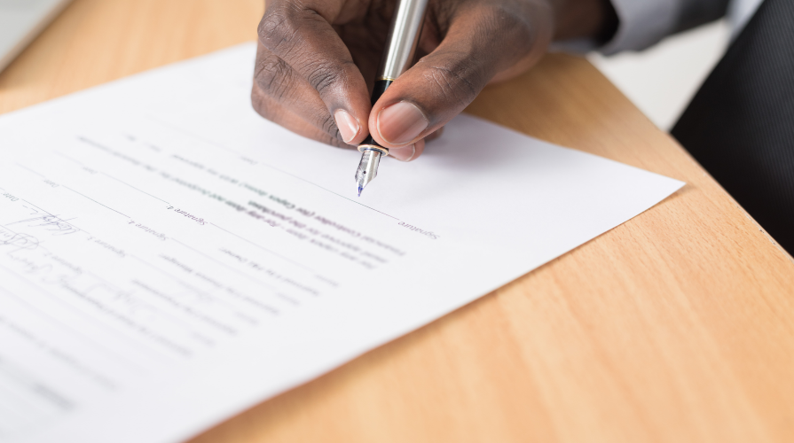 photo of a man's right hand signing a document