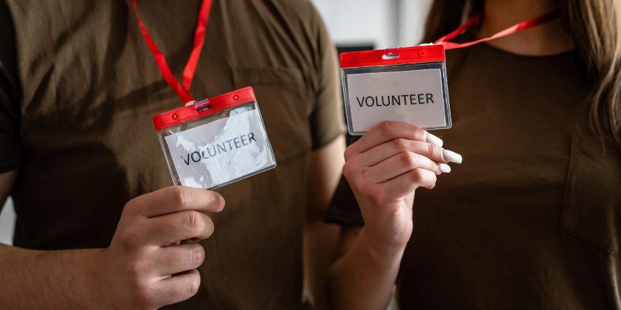Image of two people holding volunteer badges