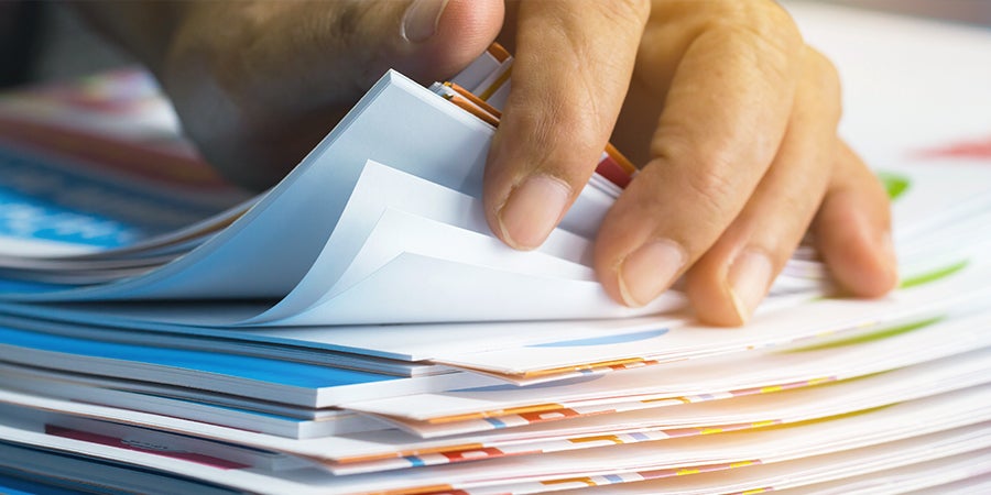 Office employee thumbing through stack of paperwork