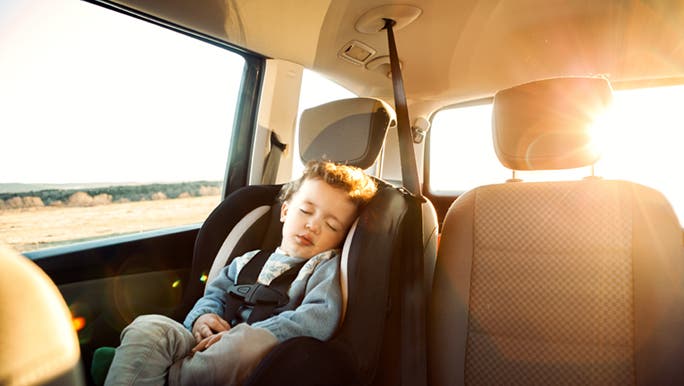 A child is asleep in a car seat while their parents wonder when kids stop napping. 