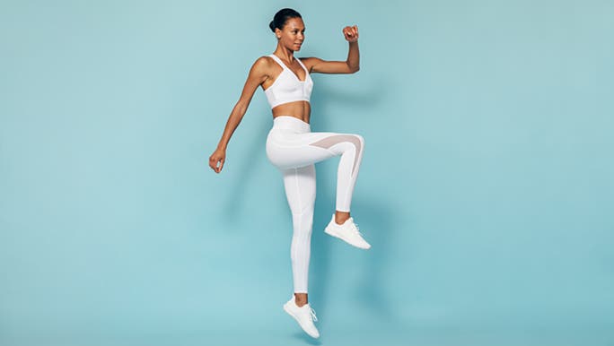 A woman jumps into the air with strength and poise because she has learned how to get motivated to exercise. 