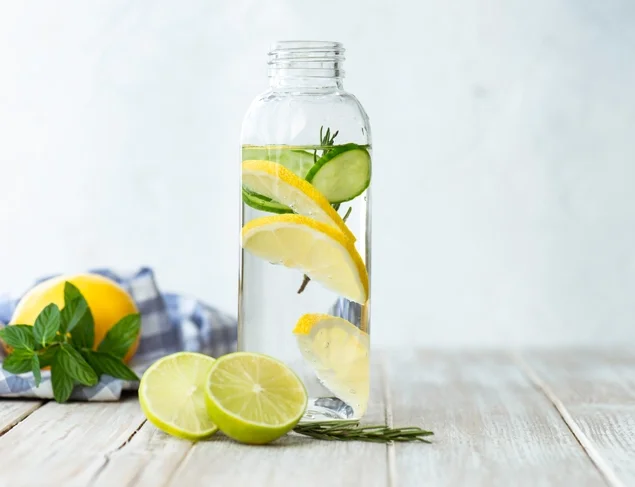 Glass bottle of water with fresh lemon slices, cucumber and mint