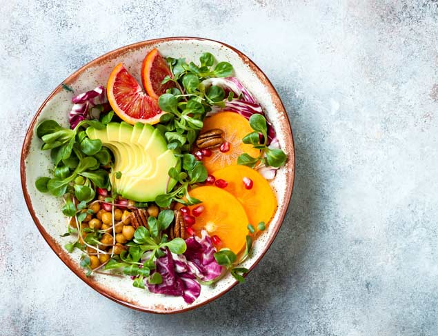 Vegan, detox Buddha bowl with turmeric roasted chickpeas, greens, avocado, persimmon, blood orange, nuts and pomegranate