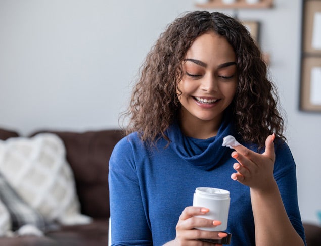 Woman in a blue top moisturising her hands