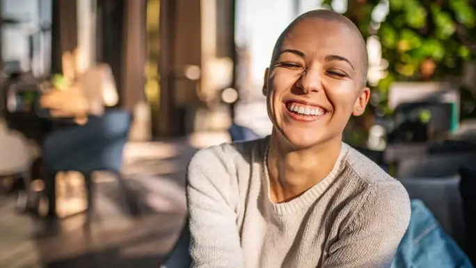 Young woman with close-cropped hair with a big smile and eyes closed