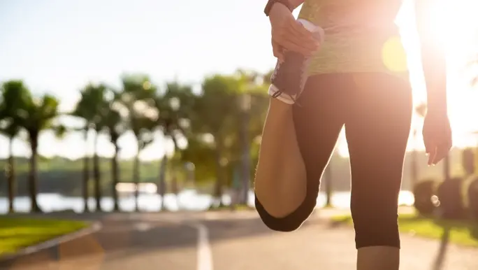 Woman doing a runner's quad stretch at the start of a run