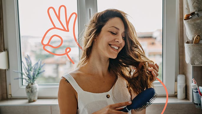 Smiling woman brushing her long brown hair