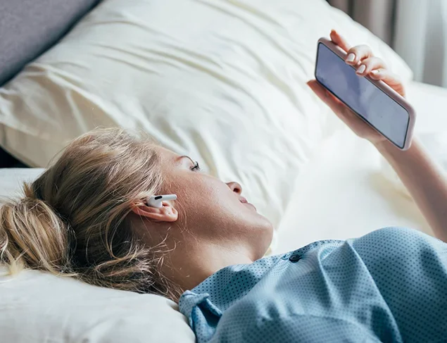 Woman lying awake in bed looking at her mobile phone