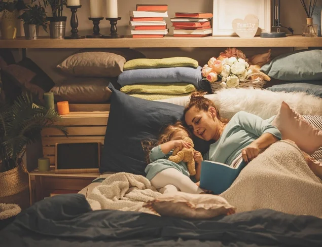 Mum and daughter tucked up in bed reading a book