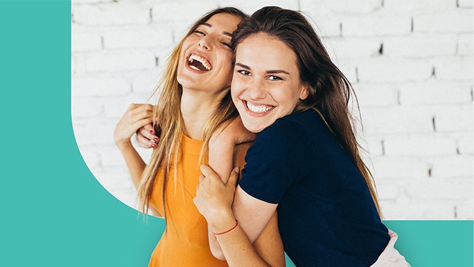 Two female friends laughing and hugging