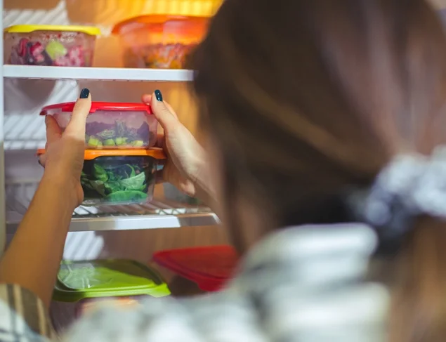 Woman putting her low FODMAP meal prep containers in the fridge