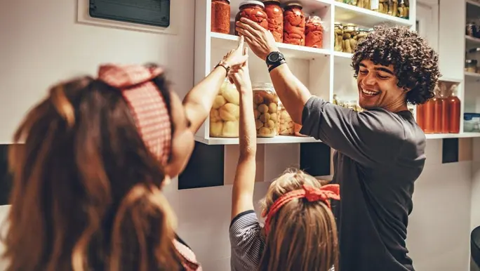 A happy family takes jars with pickled vegetables from the pantry shelf.