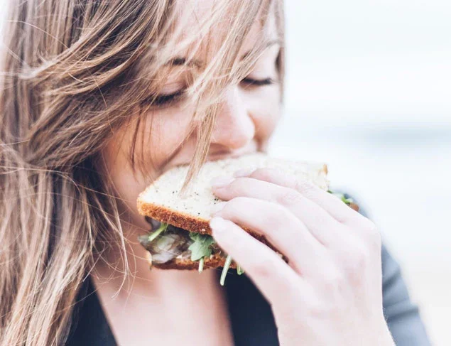 Young woman eating a sandwich made with low FODMAP bread