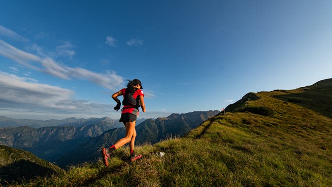 A woman runs up a mountain at altitude while she is thinking about joining an altitude gym.