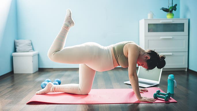 A woman is on a yoga mat doing pelvic floor exercises in pregnancy.