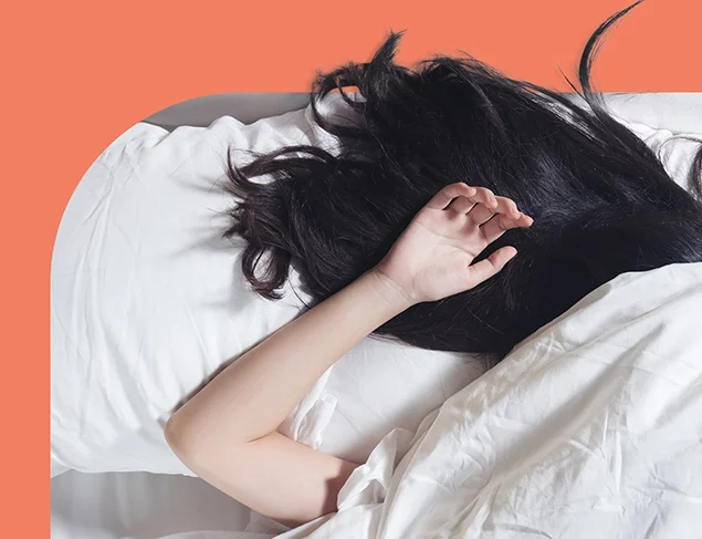 Woman fast asleep under a white sheet, only her black hair and one arm is showing.
