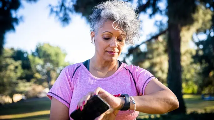 Woman in a purple workout top with a smartwatch fitness tracker about to start a run