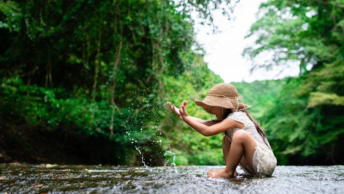 Young girl having fun and playing in the water in the bush