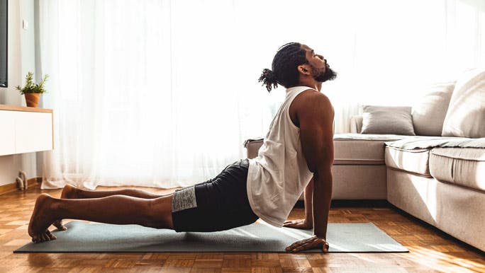 Man doing yoga at home he is in upward facing dog yoga pose