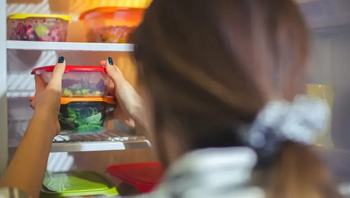 Woman putting her low FODMAP meal prep containers in the fridge