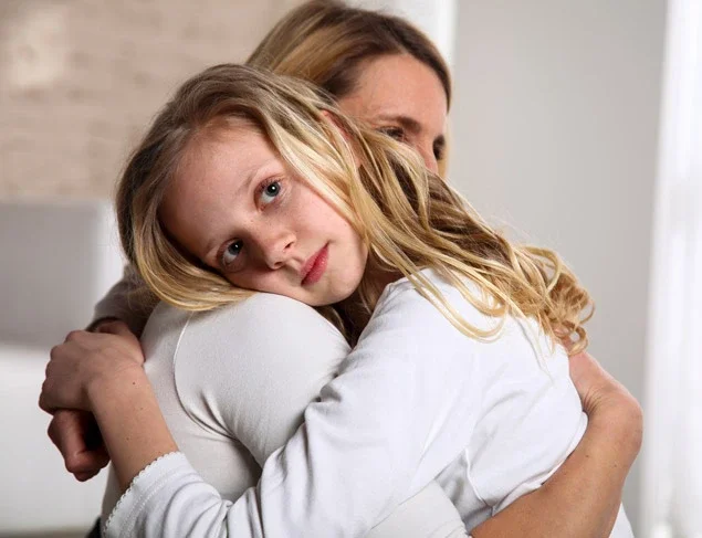 Mum giving her daughter a comforting hug