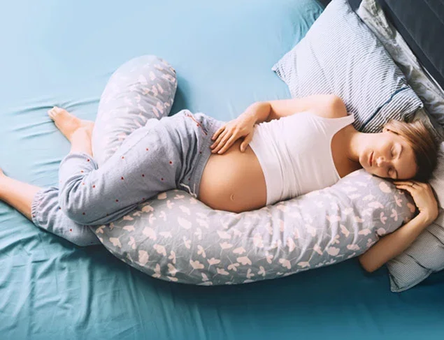 Pregnant woman in a deep sleep using a body pillow