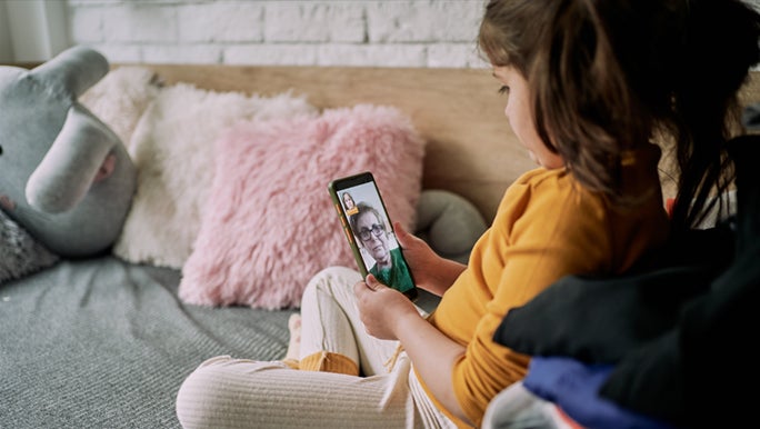 A little girl is video chatting to her grandma while her parents work from home.