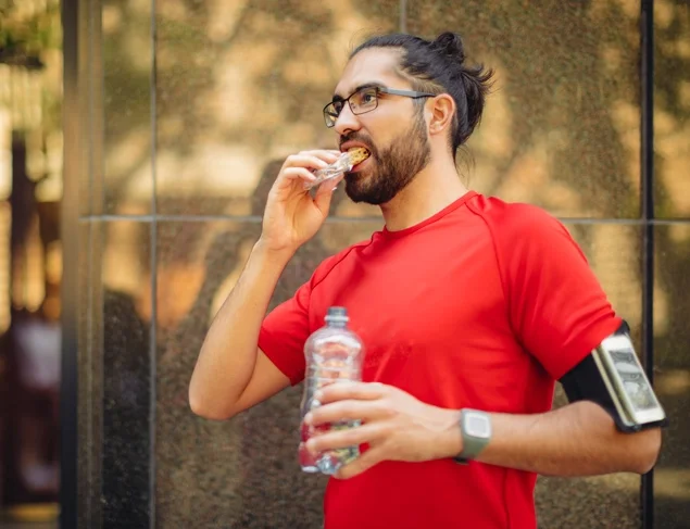 Active man in a red t-shirt snacking on a high fibre muesli bar