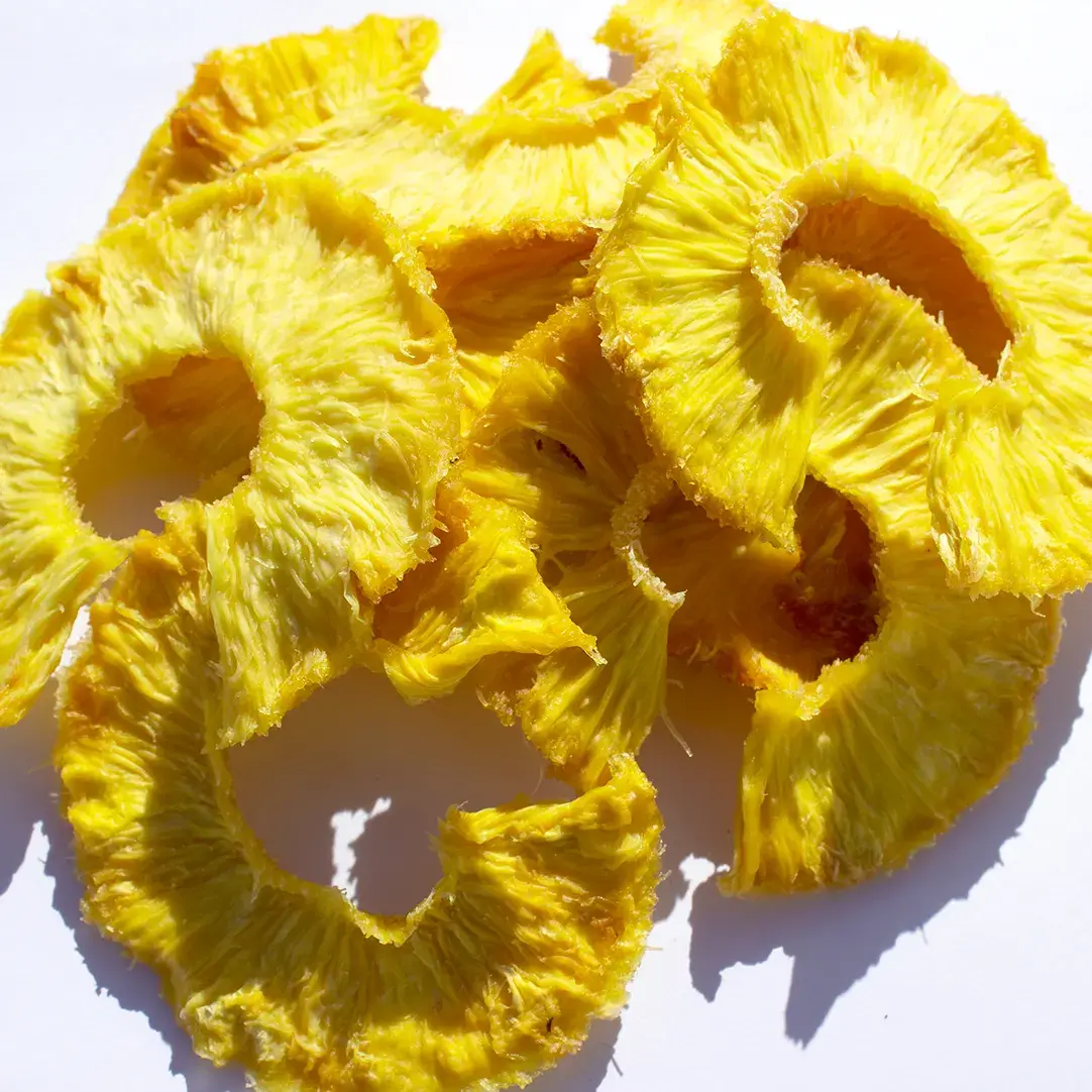 Overhead shot of rings of dried pineapple against a white background.