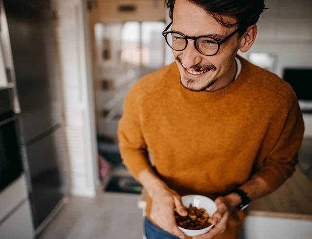 happy and healthy young man holding a bowl full of nuts