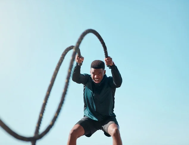 Man in black active wear doing a H.I.I.T workout with battle ropes