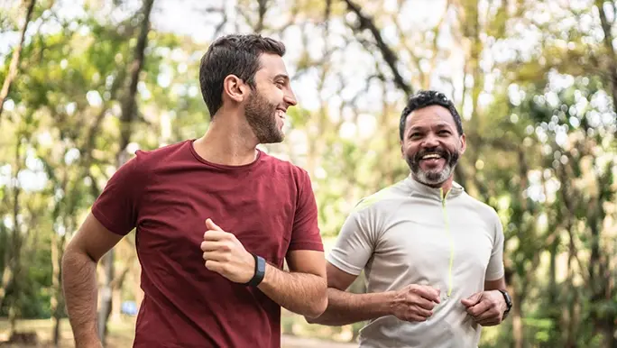 Two men are running in a park.