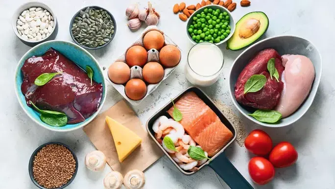 Zinc foods including meat, seafood nuts, seeds and cheese laid out on a white marble bench top 
