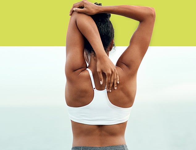 Woman in white crop top doing a tricep stretch