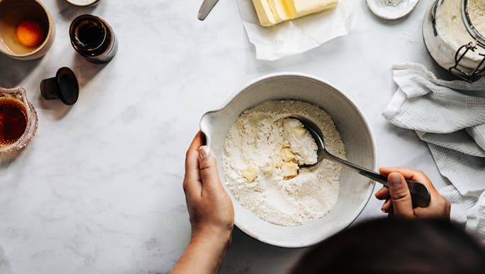 A person is stirring a bowl with cake batter and thinking, how much sugar is too much?