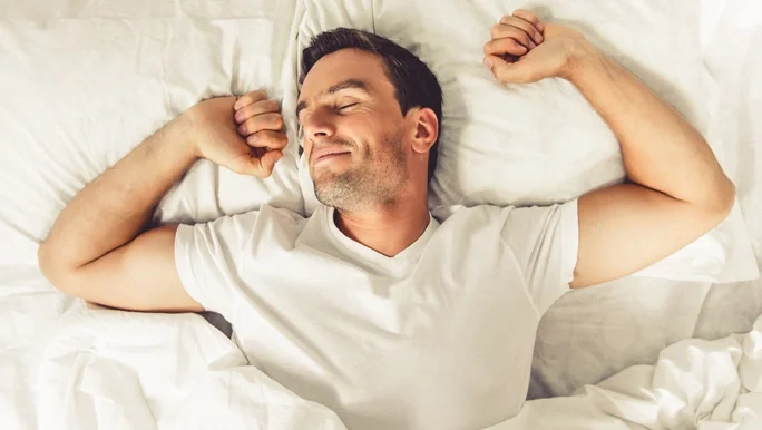 Man waking up and stretching after a good night's sleep