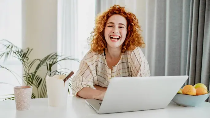 Laughing and relaxed woman with curly red hair working from home