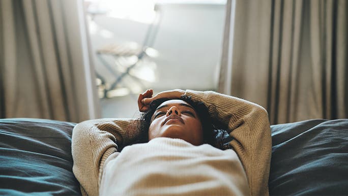 Lady lying in bed reflecting on the effects of alcohol on her health.