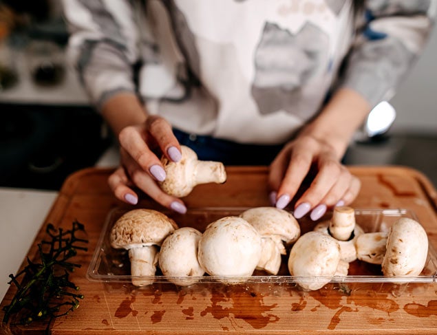 Woman preparing mushrooms on a wooden chopping board