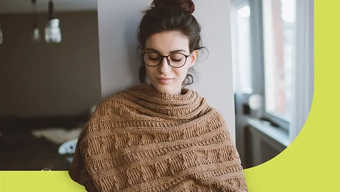 Young woman at home wrapped in a knitted shawl