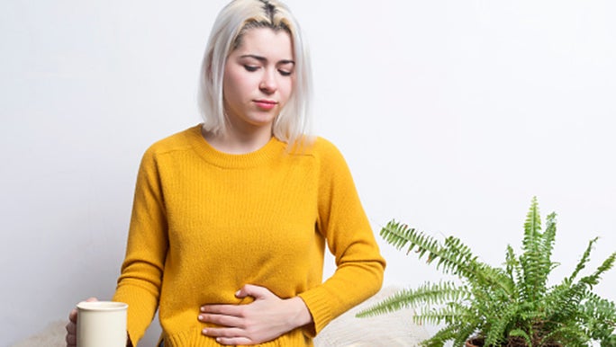 woman-sitting-with-tea-holding-her-stomach-thinking.jpg