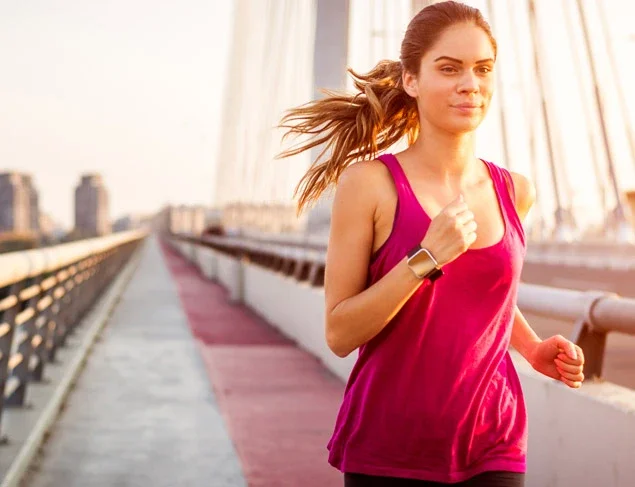 Woman having an early morning run in the city wearing a smart watch tracker