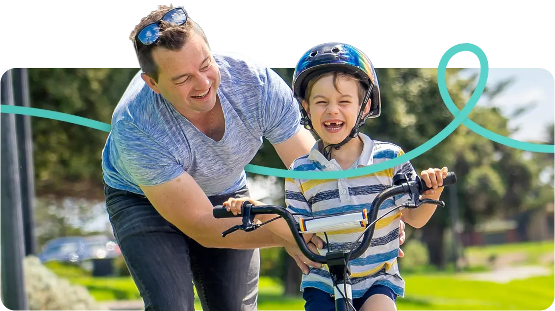 Father helping son ride his bike on a sunny day