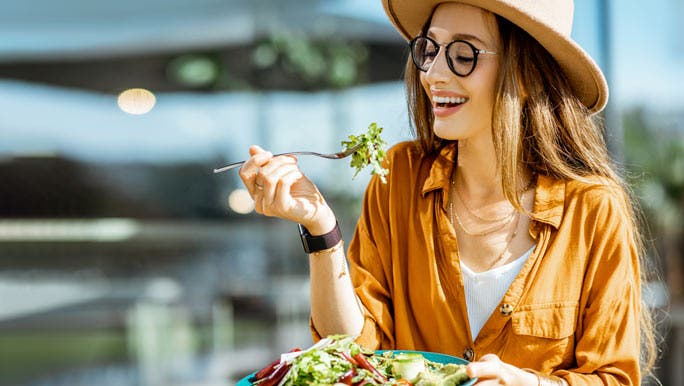 Young woman enjoying a plate of salad at an outdoor cafe