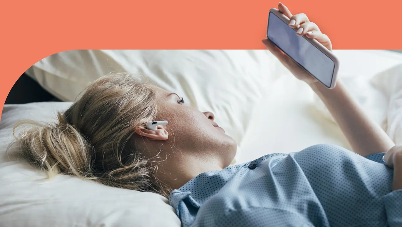Woman lying awake in bed looking at her mobile phone