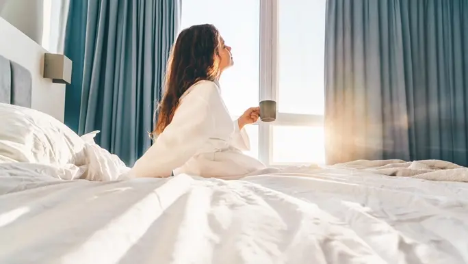 Woman relaxing in bed with a herbal tea