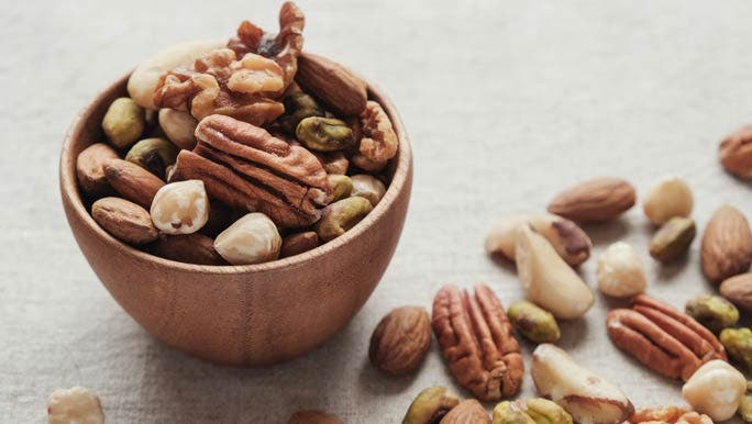 Mixed raw nuts in a small wooden bowl