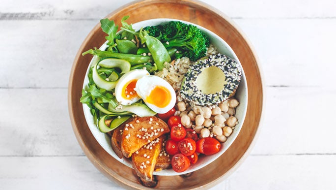 Salad bowl with fresh greens, roasted sweet potato, chickpeas, tomatoes and avocado