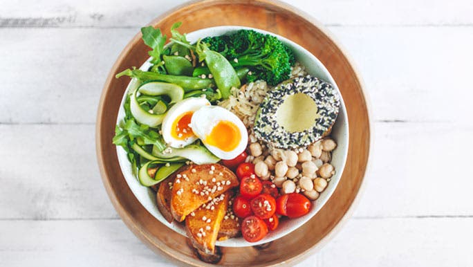 Salad bowl with fresh greens, roasted sweet potato, chickpeas, tomatoes and avocado